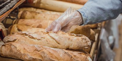 Žena v plastové rukavici vybírá bagetu