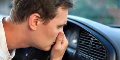 Muž si drží nos před průduchy v autě.