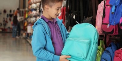 Malý chlapec si v obchodě vybírá batoh do školy