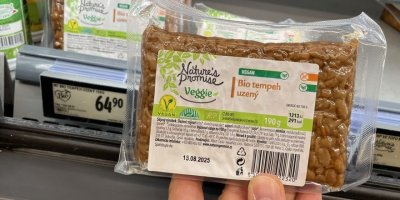 Ruka držící balení uzeného tempehu u regálu v supermarketu