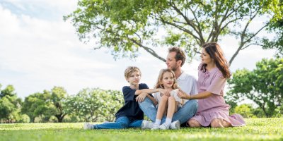 Rodina se dvěma dětmi sedí na trávě