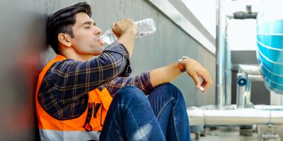 Muž vysíleně sedí a pije vodu