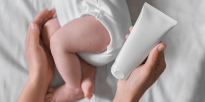 Miminko a matčina ruka držící krém