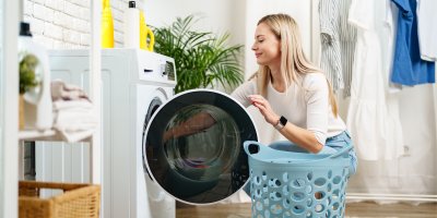 Žena dává prádlo do pračky
