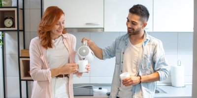 Muž nalévá ženě nápoj z konvice do hrnku