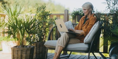 Žena sedí na terase s notebookem