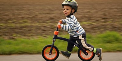 Chlapeček jede na jednostopém odrážedle na cyklostezce