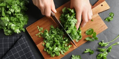 Člověk krájí koriandr na prkénku