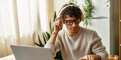 Mladý muž pracuje u počítače se sluchátky