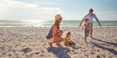 Rodiče a dvě děti si hrají na pláži u moře