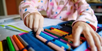 Holčička vytahuje psací potřeby ze školního penálu