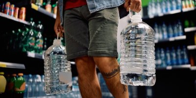 Muž kupuje v obchodě balenou vodu