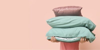 Člověk drží polštáře a přikrývku