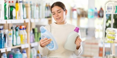 Mladá žena si v drogerii vybírá prací prostředek