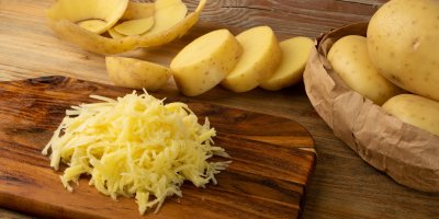 Nastrouhané brambory, za nimi celé brambory