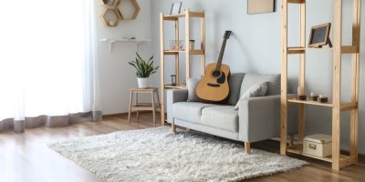 Interiér obývacího pokoje, plovoucí podlaha s kusovým kobercem, světlá pohovka, dřevěné police, dekorace