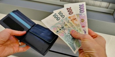 Žena si vkládá peníze z bankomatu do peněženky