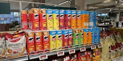 Pringles a další slané pochutiny v regálech supermarketu