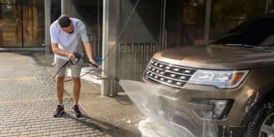 Muž umývá auto v samoobslužné ruční myčce