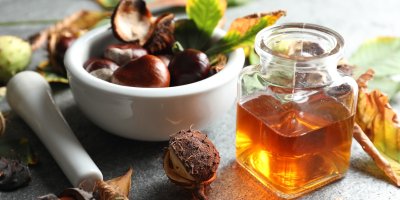 Sklenice s tinkturou vedle misky kaštanů