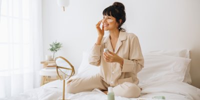 Žena si maže krém v posteli, zrcadlo