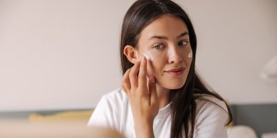 Mladá žena si nanáší krém na obličej