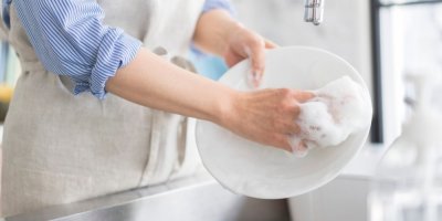 Žena myje talíř houbičkou