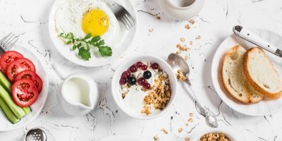Ovesná kaše, chléb, vejce a zelenina na bílých talířcích na stole
