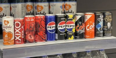 Kolové nápoje v plechovkách v regálu supermarketu