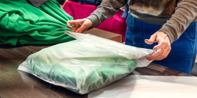 Žena balí oblečení do igelitového sáčku