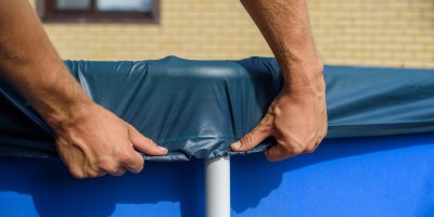 Muž přetahuje plachtu přes okraj bazénu