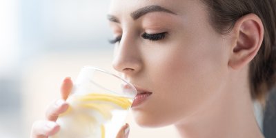 Žena pije vodu s citronem