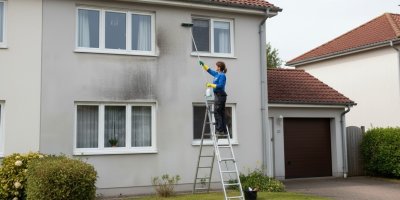 Žena čistí fasádu domu 