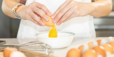 Žena rozbíjí vejce do misky