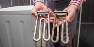 Muž v koupelně drží v rukou starou a novou topnou spirálu