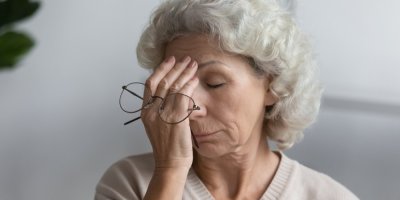 Unavená starší žena s brýlemi v ruce