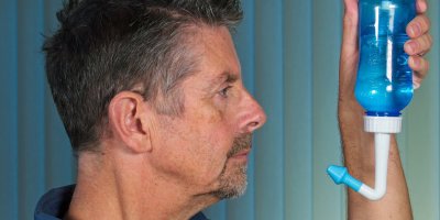 Muž v rukou drží modrou lahev