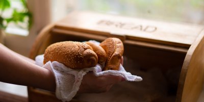 Žena vyndává rohlíky z chlebníku