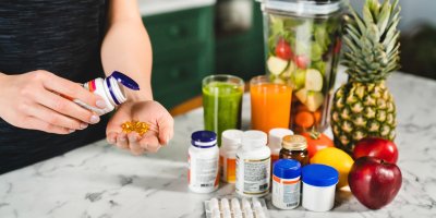 Žena si dává do dlaně vitamíny z lahvičky