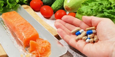 Dlaň s vitamíny, vedle losos a zelenina