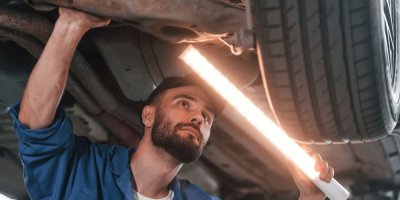 Automechanik prohlíží spodní část auta