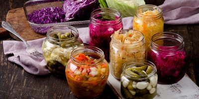 Sedm zavařovacích sklenic s kvašenou zeleninou, hlávkové zelí