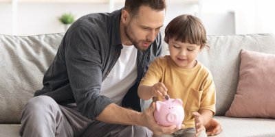 Otec s dítětem dávají minci do prasátka