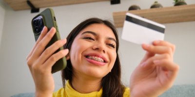 Dívka drží v rukou mobilní telefon a kreditní kartu