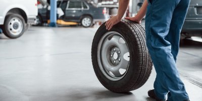 Muž v pracovním oděvu drží pneumatiku