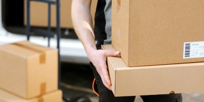 Kurýr drží v rukou balíčky