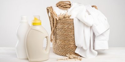 Prací prostředky a koš s bílým prádlem