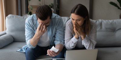 Mladý pár sedí na sedačce a dívá se do počítače