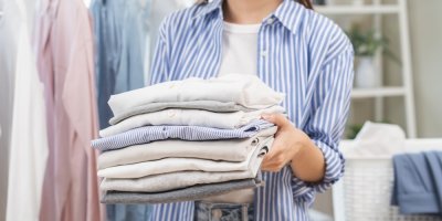 Žena drží hromádku poskládáného prádla.