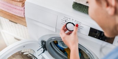 Žena nastavuje prací režim na pračce.